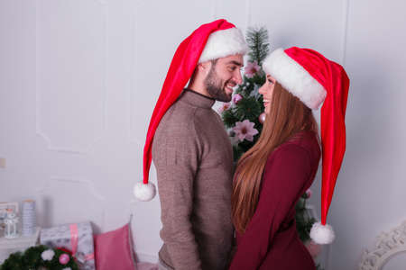 A guy with a girl are standing next to each other looking at the background of a Christmas treeの写真素材