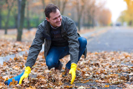 The man is cleaning the fallen leaves in the autumn park.の写真素材