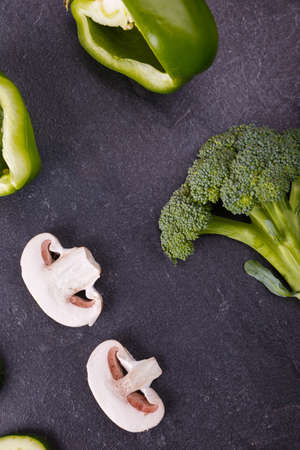 Close-up of broccoli and bell pepper, slices of cucumber, and champignons on a black background, close-up, beautiful concept of healthy eatingの写真素材