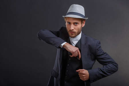 Gangster pulls out a gun from under the jacket on a gray backgroundの写真素材