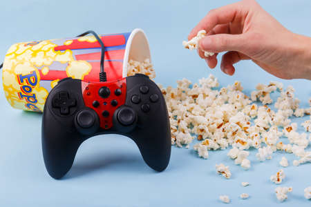 The joystick black with the red center leaned on an inverted bowl with scattered popcorn and the...