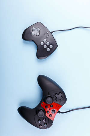 Two joysticks one old another new generation lie crooked on a blue backgroundの写真素材