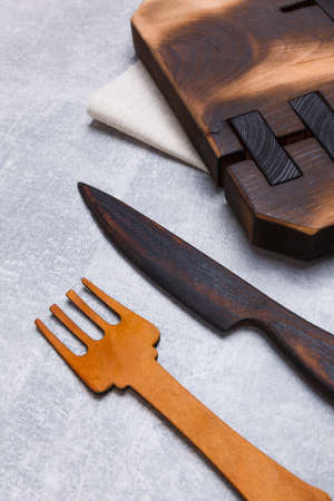A wooden dostichka on a towel with a wooden fork and knife is shown not completely close-up on a gray background. View from aboveの写真素材