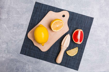 A wooden anchorage on which a lemon on a towel and a tool for squeezing juice on a gray background. View from aboveの写真素材