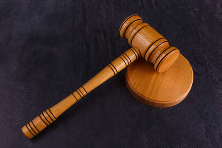 The hammer of the wooden judge lies on a wooden stand on a stone background. Top view from an angleの写真素材