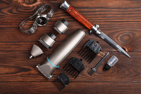 Trimmer with a set of different attachments next to a knife and clock on a wooden background