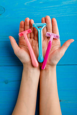 Shaving machine of different colors on the palms of a close-up on a blue wooden backgroundの写真素材