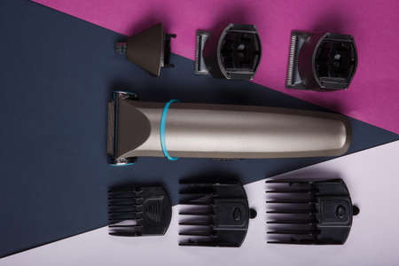 The trimmer with different nozzles on the sides lies horizontally on a dark, pink and gray background. Top view of a closeupの写真素材