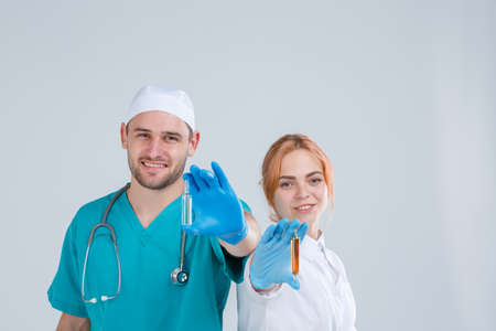 A nurse and a doctor in uniform are holding a glass ampoule with medicine. Isolation.の写真素材