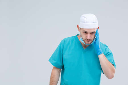 A doctor, stands with a pensive look and clings to his head. Isolation.の写真素材