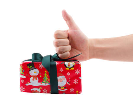 Hand showing a thumb up next to a gift box decorated with a dark green ribbon. Isolated on white background.の写真素材