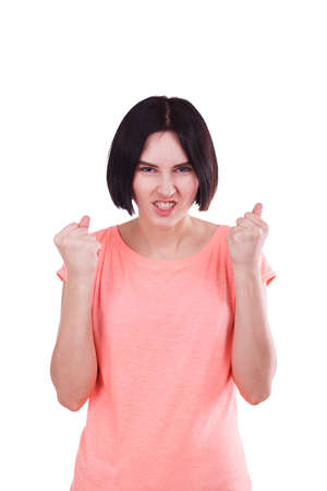 An evil girlshows an aggressive emotion, clenching her teeth and hands tightly into fists. Isolated.の写真素材