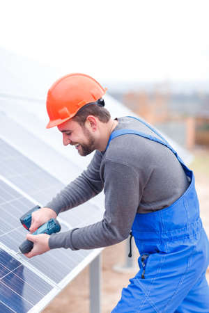 A worker is drills a solar battery panel. Outdoors.の写真素材