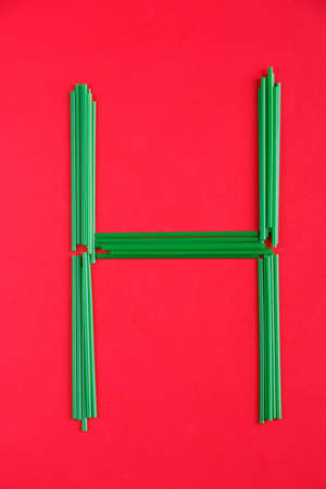 On the red background there is a green letter Hof plastic tubes.の写真素材