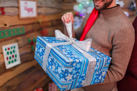 The happy guy opens his gift box. Christmas atmosphere. Indoors.