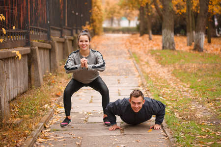 Young couple, athletes, train in the autumn park