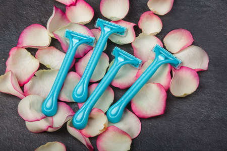 Close-up of a blue disposable razor with rose petals.