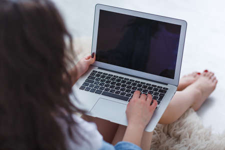 Girl with laptop close-up near the bed on a white backgroundの写真素材