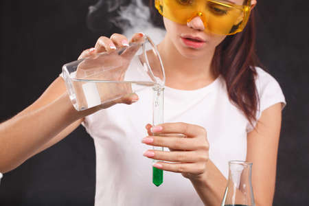 A girl lab assistant poured liquid into a test tube on a black backgroundの写真素材
