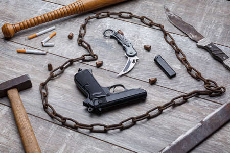 A pistol, knife, metal chain, beat, a hammer and several cigarettes with a cigarette lighter.の写真素材