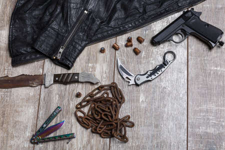On the floor there is a jacket, a chain, cartridges, a pistol and several knives.の写真素材