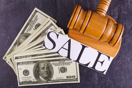 Sale on the background of a hammer of the auctioneer and a bunch of bills.の写真素材