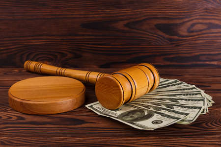 On the wooden table there are dollar bills, a auction hammer and a stand.の写真素材