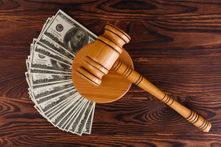 A auction hammer on a stand, next to dollar bills.の写真素材