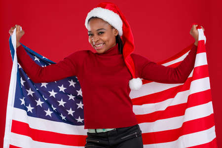 A happy African American girl is holding a American flag behind her back and smiling .の写真素材