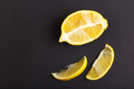 Half and two slices of lemon on a black background are. Vitamin C.の写真素材