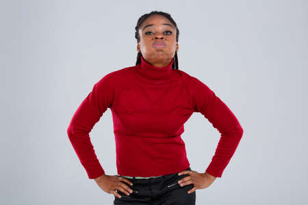 A funny African-American girl pouting her lips and holding her arms to the side.