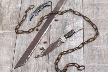 Chain with knives of different small, homemade and homemade machetes on a wooden floor