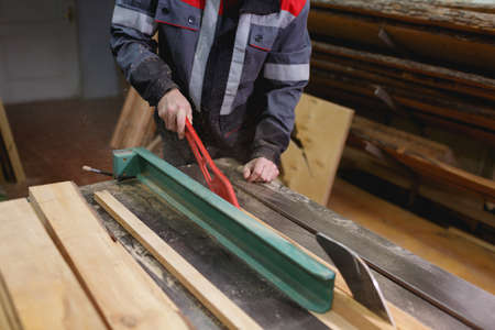 Workers in uniform spend a board on sawing by the special tool that would not damage hands