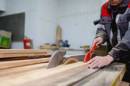The worker in the form and focus holds the board by cutting with a special tool so as not to damage...