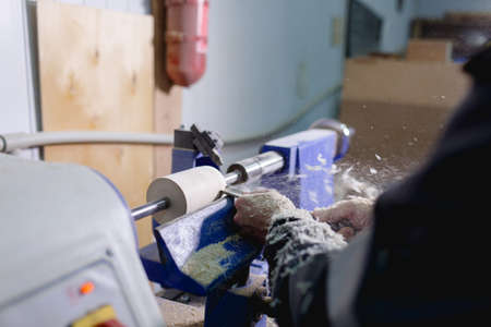 Hands of the worker with the tool give an ideally round shape to the workpiece on the machine. The...