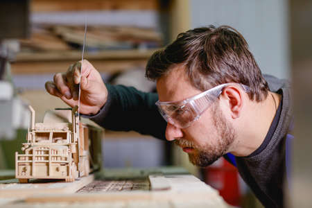 The worker makes measurements of the cabin on a wooden truck close-up in the workshop on a blurred backgroundの写真素材