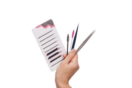 Hand holds a palette and tools for eyelash extension close-up on a white isolated background
