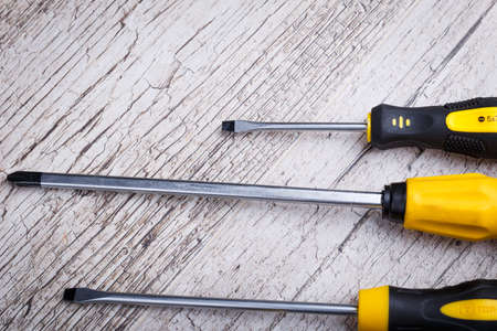 Screwdrivers lie horizontally close-up on a gray wooden floor. View from aboveの写真素材
