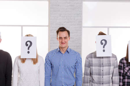 A guy between people with closed faces with a leaf with a question mark