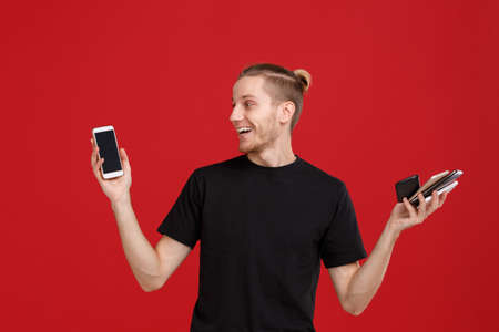 A guy holds a lot of phones in his hands on a red background