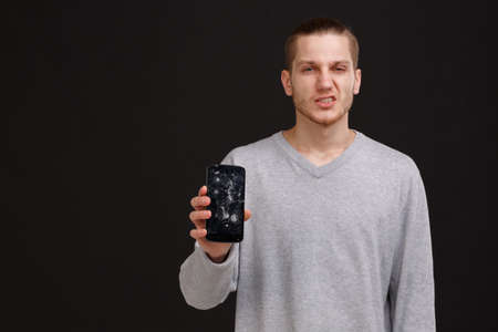 A guy shows a broken phone on a black background...