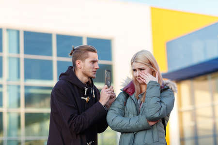 A guy shows with two hands a broken phone to a girl on a blurred background