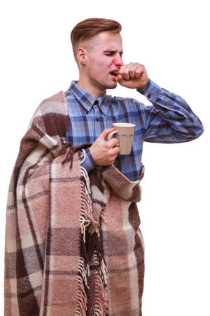 Sick guy sneezes and covers his mouth with his fist on a white isolated backgroundの写真素材