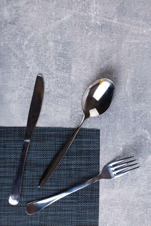 At the corner of the serving napkin is a spoon, fork and knife.の写真素材