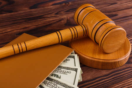 An auctioneers hammer on a round stand, a notepad in which there are a lot of dollar bills.