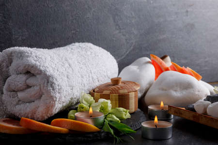 A set of bath towel, candles, pebbles and grapefruit for a spa treatment.