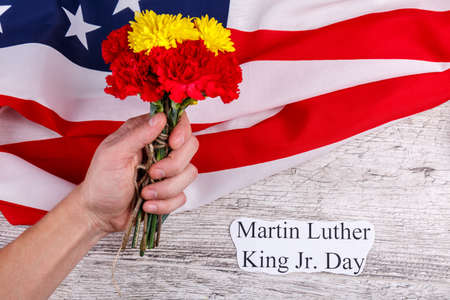 The hand holds a bouquet of carnations against the American background and the inscription of Martin Luther King Jr. Dayの写真素材
