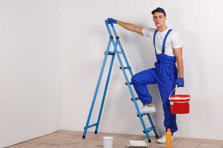 A worker climbs on a ladder with a bucket on a white backgroundの写真素材