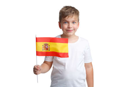 A young boy holding a flag of Spain on a stick with a slight smile on a white isolated backgroundの写真素材