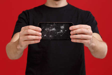 A guy holds a broken mobile phone.の写真素材